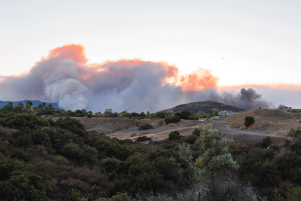 A distant cloud of smoke rising from the mountains of California during the fires