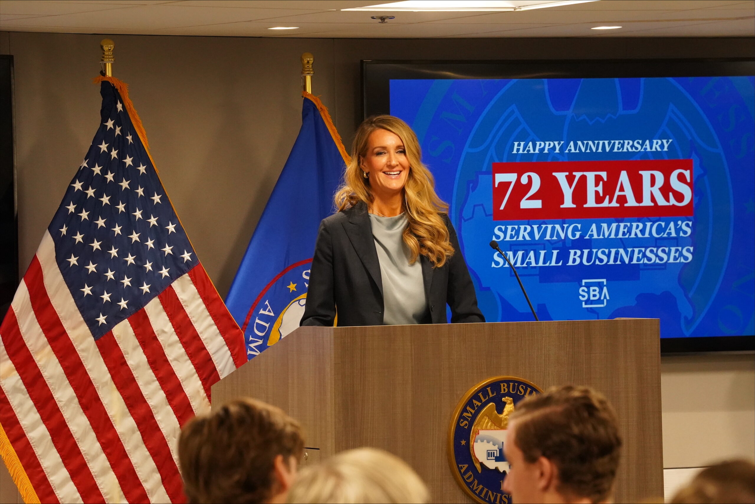 Administrator Loeffler behind a podium, presenting on 72 years of SBA serving small businesses.